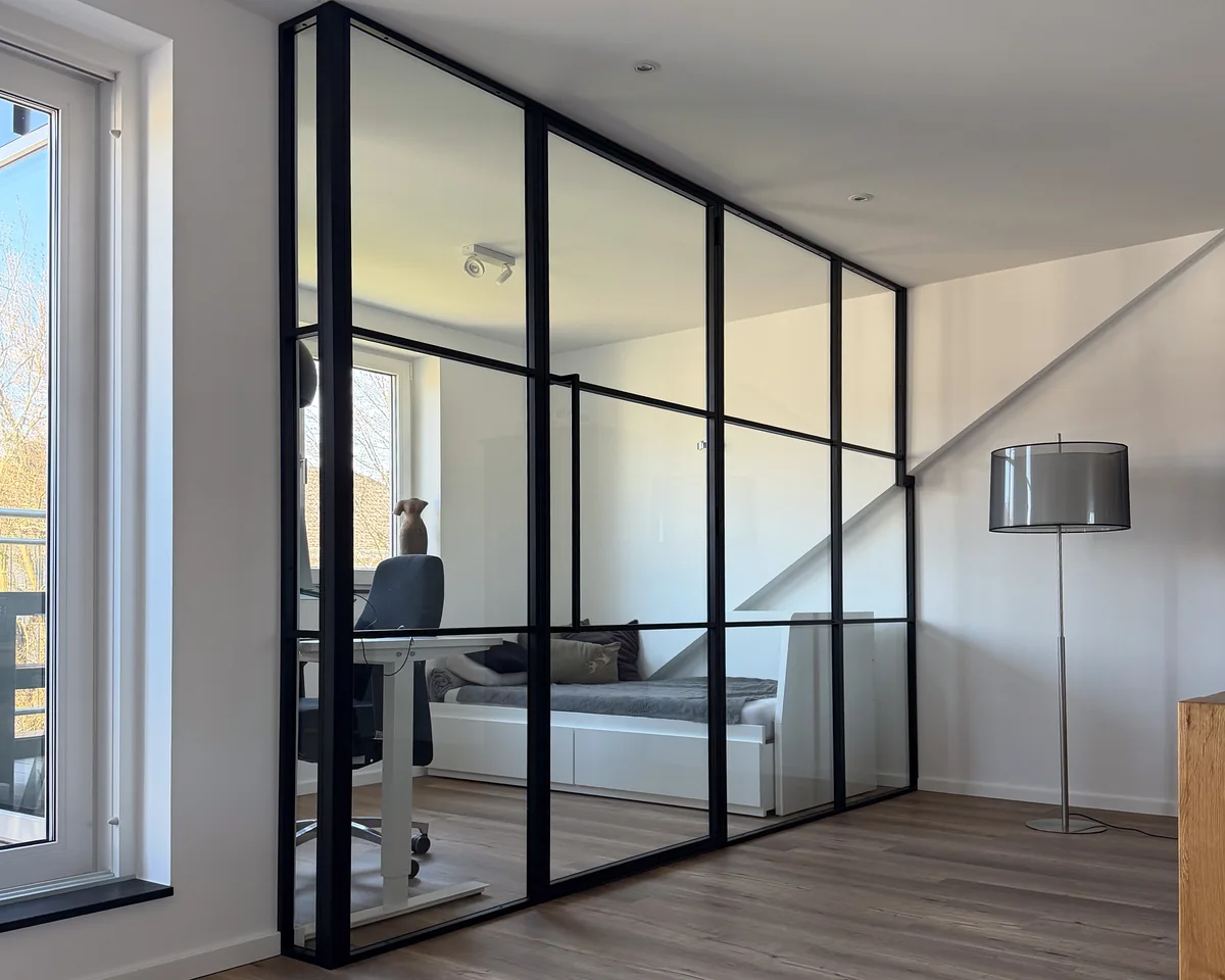 Glastrennwand als Raumteiler unter der Dachschräge im Arbeitszimmer