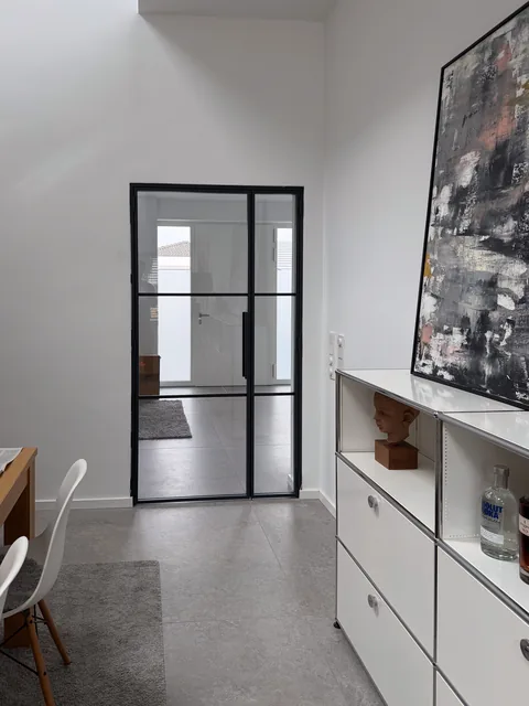 Drehtür im Eingangsbereich neben Sideboard und großformatigem Bild