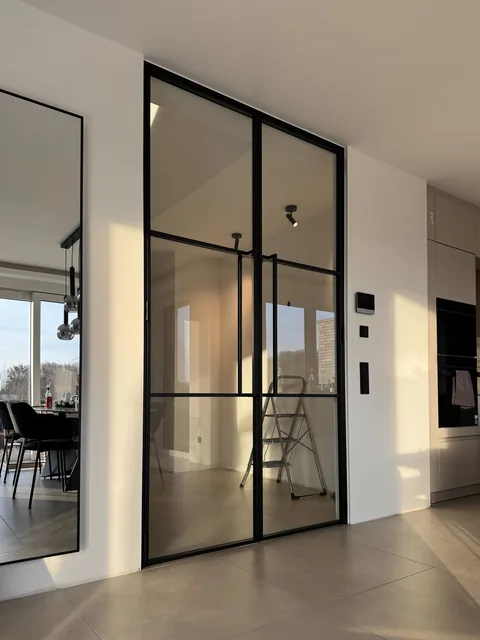 Raumhohe Stahl-Glas-Wand mit Drehtür zwischen Küche und Esszimmer