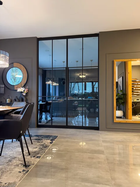 Pivottür aus Stahl und Glas im Esszimmer bei Abendbeleuchtung