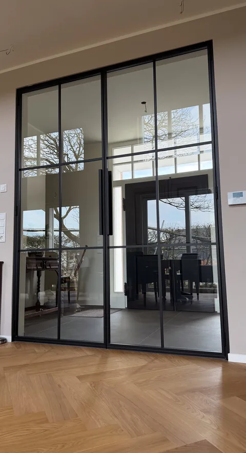 Großformatige Stahl-Glas-Anlage mit Drehtür und Festelementen im Wohnbereich